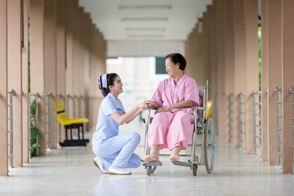 nurse holding the hand of a patient that is in a wheelchair