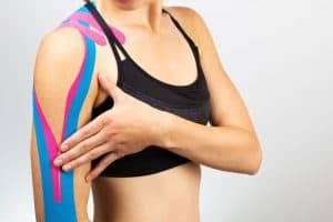 woman with sports tape on her injured shoulder 